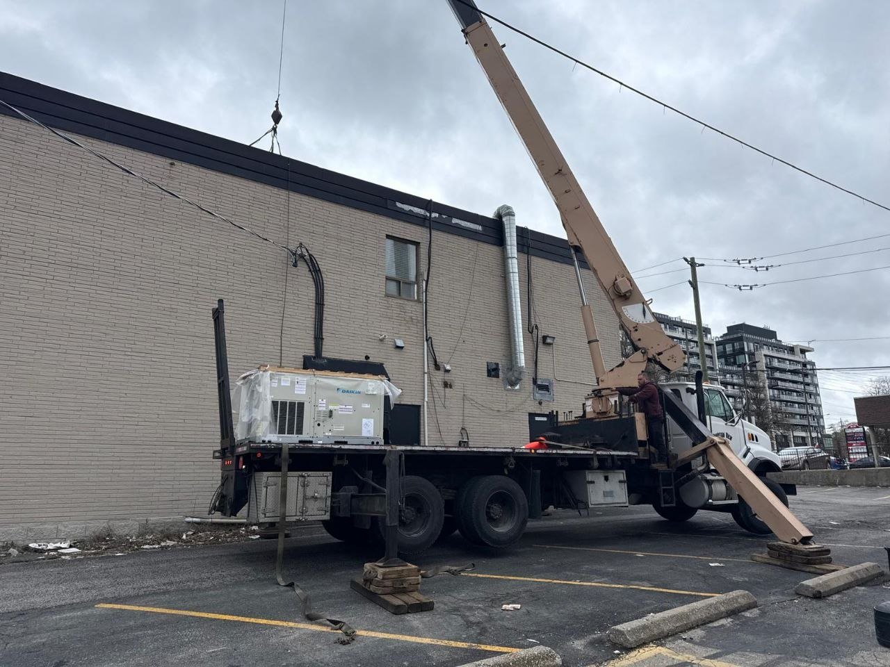 Crane lifting rooftop HVAC unit onto commercial building Toronto